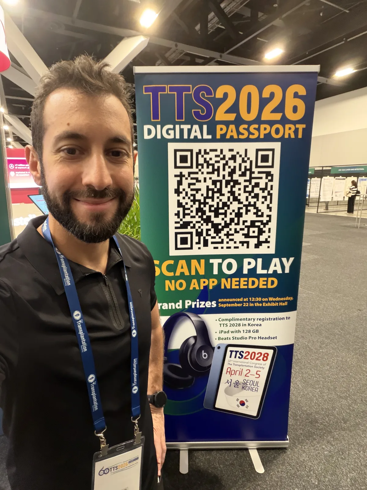 A member of the organising team smiling beside a passport banner